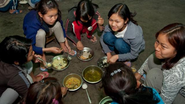 The children eat squatting on the floor, It is only the adults who sit on chairs at tables to eat, on January 27, 2011 in Baktawang, Mizoram, India.