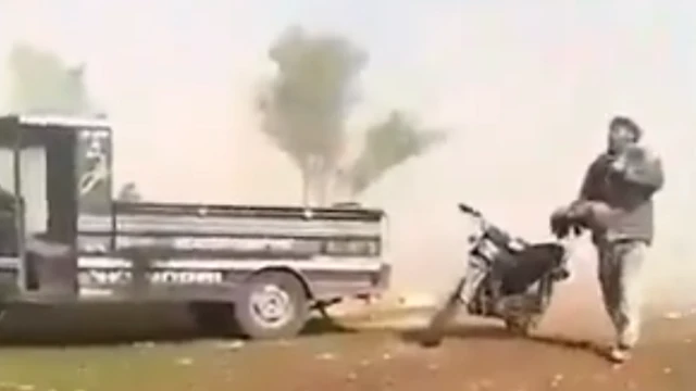 صورة من المقطع تظهر الوالد وهو يحمل الطفل مبتور الساقين