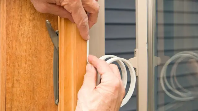 Un homme met du ruban adhésif sur une fenêtre