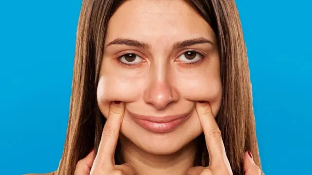Mujer joven forzando una sonrisa.
