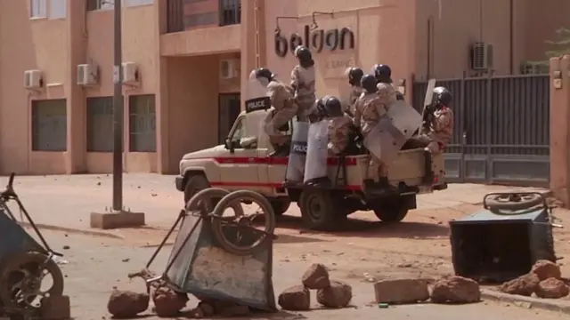 Riot policemen driving towards protesters at a makeshift checkpoint in Niamey, Niger