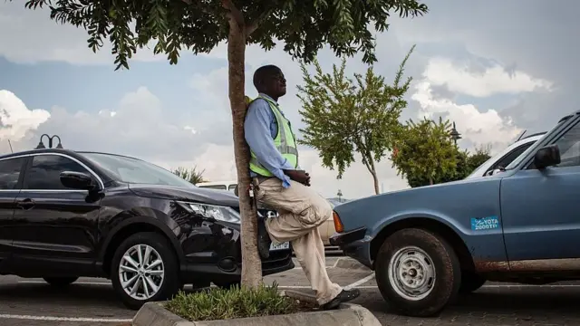 Homem encostadoganhar dinheiro apostas desportivasárvore vigiando carro