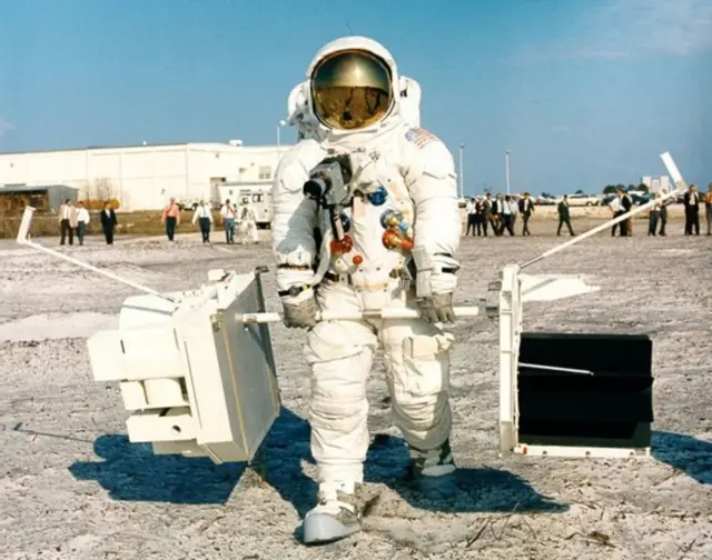 அப்பல்லோ 13 கமாண்டர் ஜிம் லோவெல் பயிற்சியின் போது புளூட்டோனியம் பேட்டரி மற்றும் அறிவியல் உபகரணங்களை எடுத்துச் செல்கிறார்