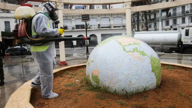 A worker wearing a protective suit disinfects a globe-shaped public garden in Algiers, Algeria - Monday 23 March 2020