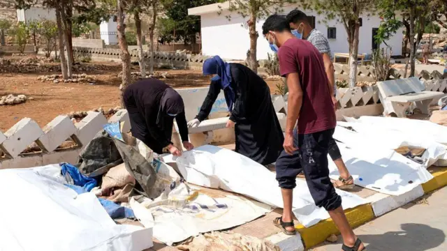 На улице в Дерне люди осматривают тела в поисках своих пропавших родных