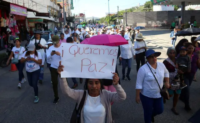 Varias personas vestidas de blanco en una manifestación en México por la paz. Una mujer lleva una pancarta en la que puede leerse: "¡Queremos paz!".