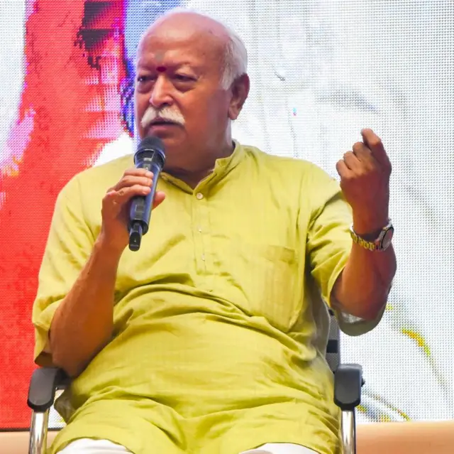 मंच पर कुर्सी बैठकर माइक से बोलते हुए आरएसएस के सरसंघचालक मोहन भागवत