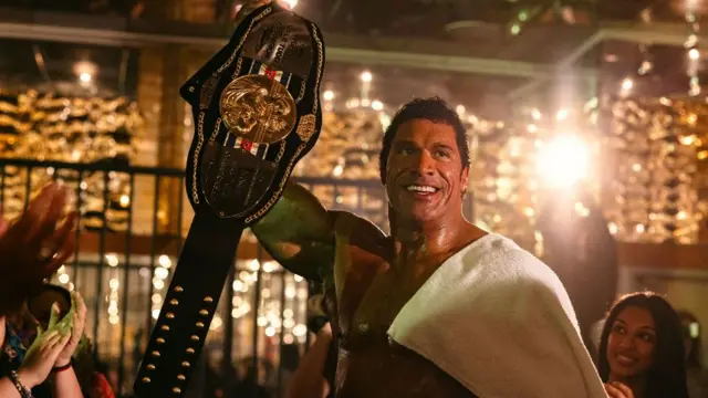Dwayne Johnson, The Smashing Machine filminde omuzlarında bir havluyla ve alkışlayan insanlarla çevrili UFC dövüşçüsü Mark Kerr rolünde.