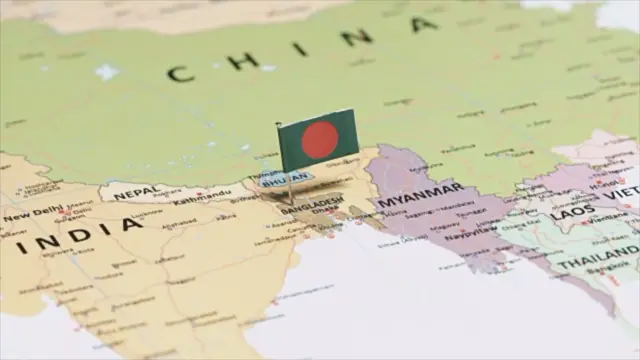 বিশ্বের একটি মানচিত্রে বাংলাদেশের নামের ওপর একটি ছোট লাল-সবুজ পতাকা পিন দিয়ে গেঁথে রাখা হয়েছে