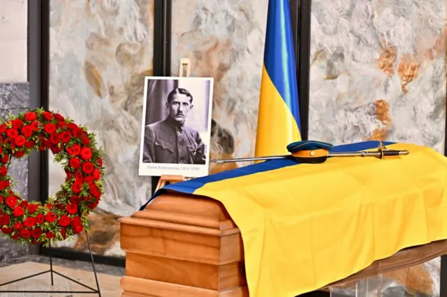 Труна, накрита українським прапором, з ексгумованими останками полковника Коновальця
