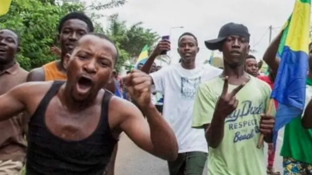 Homens negros segurando bandeiras andam nas ruas e fazem gestoswww br betanocomemoração