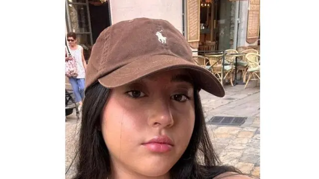 Liri Albag dey look camera. She get long, dark, straight brown hair and brown eyes, and she dey wear a brown baseball cap.