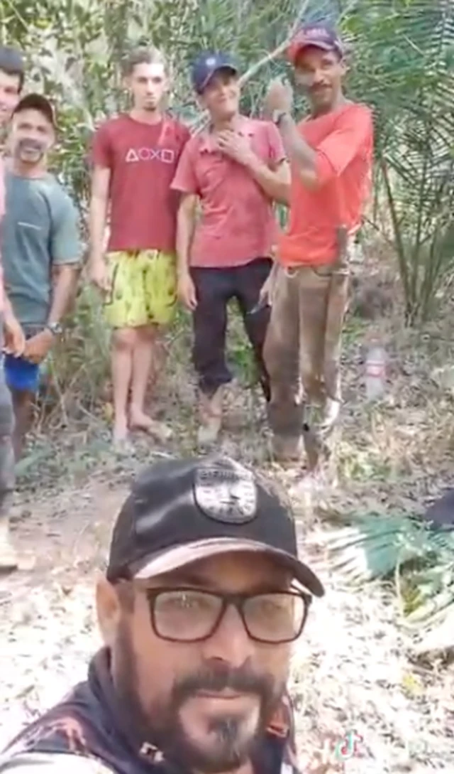 Homem de óculos e boné à frente de outros homens