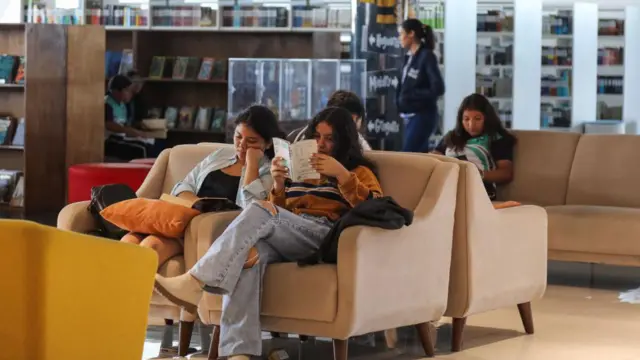 Pessoas sentadas em um sofá lendo