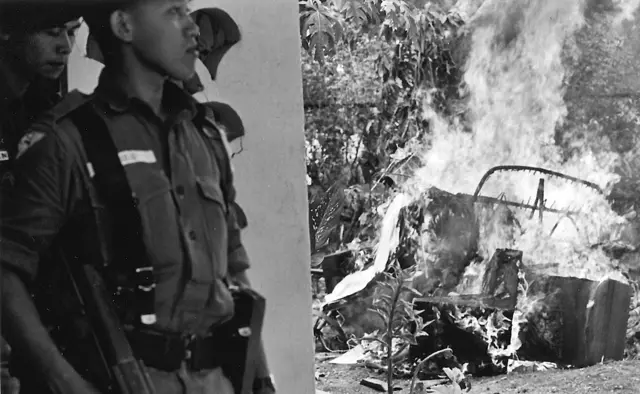 Tentara berdiri di dekat sisa-sisa kendaraan yang terbakar setelah adanya upaya penggulingan pemerintah, awal Oktober 1965.
