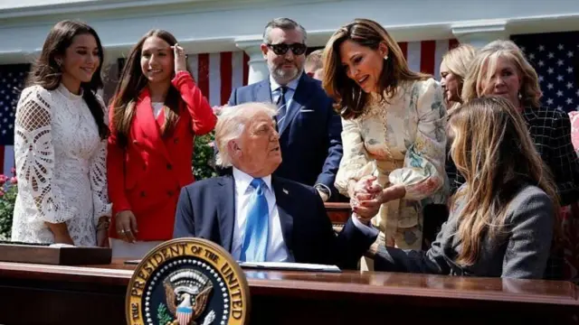 Donald Trump sentado, cumprimenta a congressista da Flórida María Elvira Salazar
