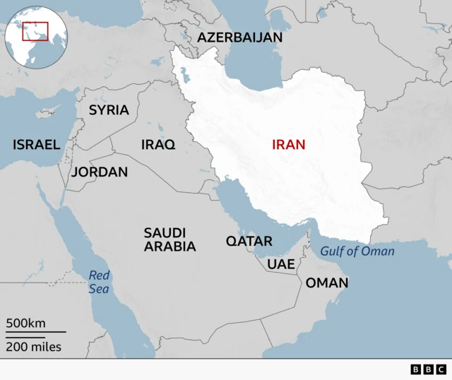A regional map highlighting Iran in white with its name in red. Surrounding countries are labeled in grey, neighbouring Iraq to the west and other Middle Eastern countries including Syria, Jordan, Israel, Gaza and Saudi Arabia, Qatar, UAE, and Oman. Bodies of water such as the Red Sea and the Gulf of Oman are marked in blue.