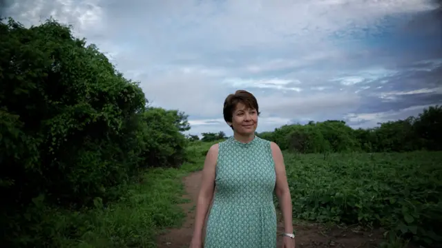 Silvana Santos andando em meio a uma área rural