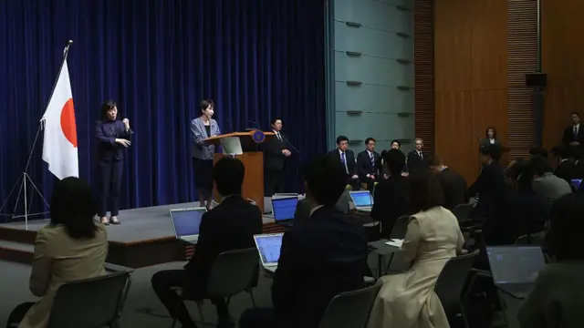 高市早苗在记者会讲台上,台下坐着手持电脑的记者