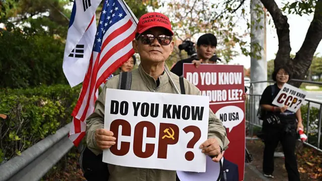 2025年10月30日,中國國家主席習近平抵達釜山參加亞太經合組織(APEC)峰會之際,一名反華抗議者在金海國際機場空軍基地外高舉寫有「你知道中共嗎?」(Do you know CCP?)的標語牌。