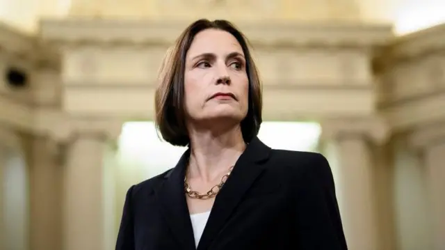 Фіона Гілл у чорному піджаку із золотим намистом дивиться вбік