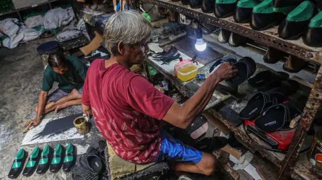 Dua pekerja menyelesaikan pembuatan alas kaki sandal kulit di rumah industri sepatu, Rejomulyo, Semarang, Jawa Tengah, Selasa (6/1/2026). 