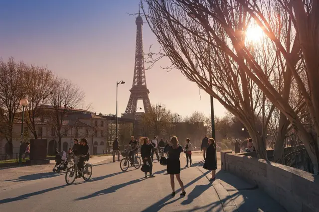 Para turis dan pengendara sepeda di hari yang cerah di dekat menara Eiffel di Paris, Prancis