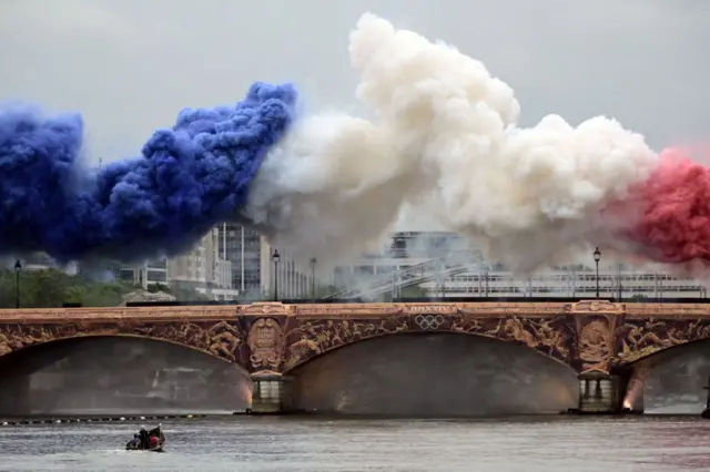 Fumaça azul, branca e vermelha sobre uma ponte do rio Sena