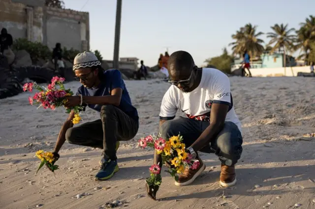 Deux jeunes tenant des bouquets de fleurs au niveau d'une plage.