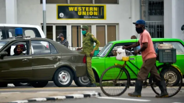 Carros e pessoas paradas em uma rua, em frente à sucursal da Western Union em Havana