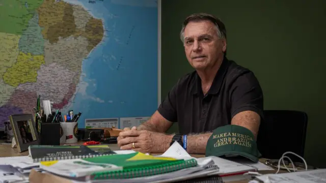 Jair Bolsonaro sentado atrás de mesa