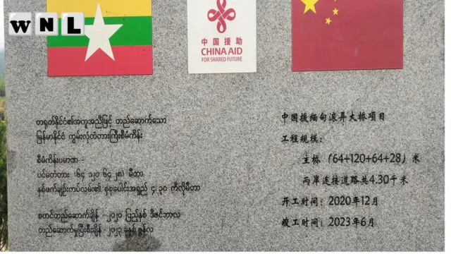 ကွမ်လုံတံတားဆောက်လုပ်မှုနဲ့ ပတ်သက်တဲ့ ကမ္ဗည်းမော်ကွန်းပုံ၊ ကွမ်လုံ တံတားဟာ သိန္နီ – ကွမ်လုံ – ချင်းရွှေဟော် လမ်းမကြီး၊ မြန်မာ နဲ့ တရုတ် နယ်စပ်ကုန်သွယ်ရေး လမ်းကြောင်းအတွက် အရေးပါတဲ့ လမ်းတစ်ခုဖြစ်ပြီး ၁၀၂၇ စစ်ဆင်ရေးအတွင်းမှာ ကျိုးကျပျက်စီးခဲ့ပေမဲ့ ၂၀၂၃ ခုနှစ်၊ ဇွန်လမှာ တရုတ်ရဲ့အကူအညီနဲ့ ပြန်လည်တည်ဆောက်ပြီးစီးခဲ့ပါတယ်။ 