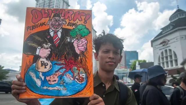 Seorang aktivis dari organisasi lingkungan Indonesia menunjukkan spanduk protes untuk memperingati Hari Bumi di sepanjang jalan pusat Kota Medan, Sumatra Utara.