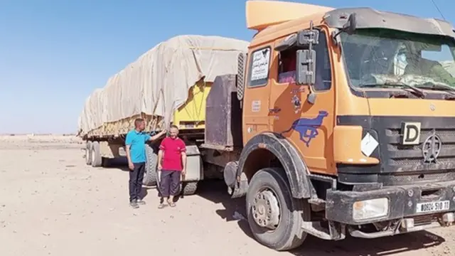 Two men stand next to a lorry stuck at the Algerian border