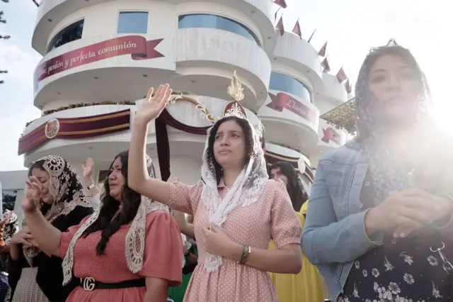 Mujeres feligresas de La Luz del Mundo, con velo en la cabeza, alzan la mano derecha mientras rezan durante la celebración llamada "La Santa Convocacion" el 14 de agosto de 2023 en la sede de la congregación, La Hermosa Provincia, en Guadalajara, México. (Foto: Leonardo Alvarez Hernandez/Getty Images)