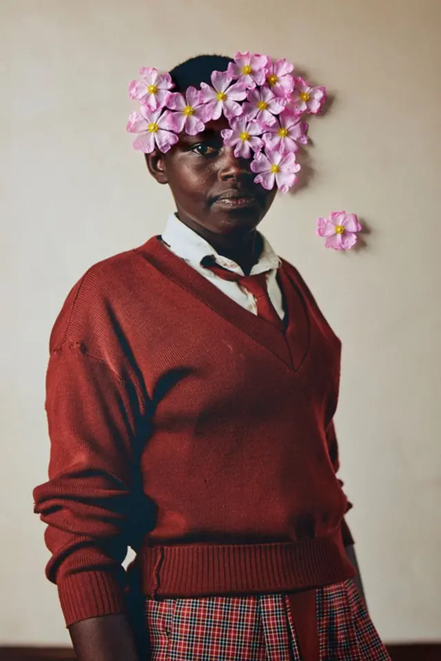 Um retratobet 365 appleuma menina queniana com flores aplicadas à fotografia