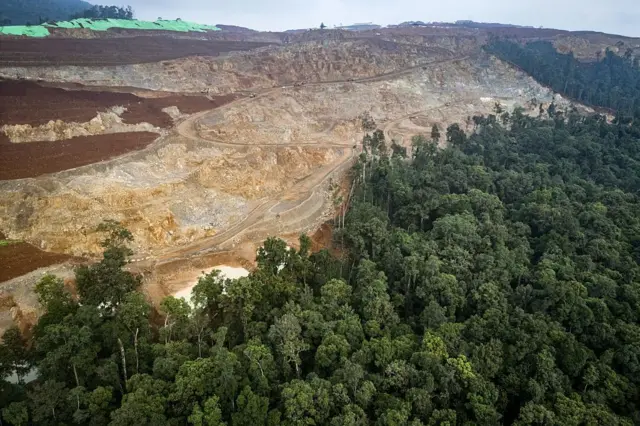 TOPSHOT - Foto udara ini yang diambil pada 16 April 2025 menunjukkan pemandangan umum lokasi pertambangan nikel dan tepi hutan tempat Bokum, anggota suku asli Hongana Manyawa, secara rutin berpatroli untuk memantau aktivitas pertambangan di Halmahera Timur, Maluku Utara. Duduk jauh di dalam hutan lebat Indonesia timur, Bokum, salah satu pemburu-pengumpul terpencil terakhir di negara ini, memiliki pesan sederhana untuk para penambang nikel yang mengancam hutan tempat tinggalnya: "Ini tanah kami." (Foto oleh AFP) / Untuk melengkapi 'INDONESIA-LINGKUNGAN-POLUSI-HUTAN-HAK-PERTAMBANGAN-ENERGI-LOGAM, LAPORAN KHUSUS' oleh Jack Moore dan Bagus Saragih (Foto oleh STR/AFP via Getty Images)