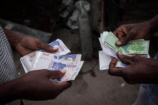 Deux hommes comptent les billets de francs CFA d'Afrique de l'Ouest pour les échanger sur le marché noir à Abidjan, en Côte d'Ivoire