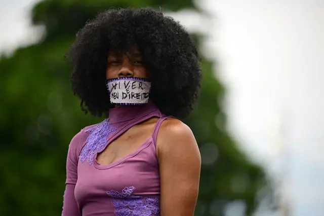 Una mujer con la boca cubierta por un cartel en el que se lee "vivir es mi derecho".