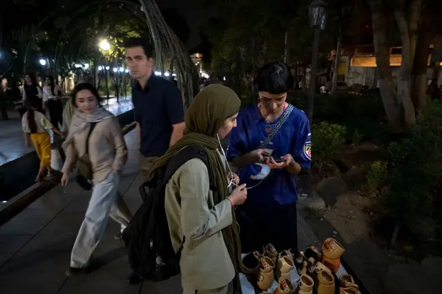 در یک پیاده‌روی در شب در شمال تهران، دو زن جوان کنار بساطی کوچک از ظروف سفالی ایستاده‌اند. یکی از آن‌ها در حال نوشتن اطلاعات روی تلفن همراه مشتری است. رهگذران از کنارشان عبور می‌کنند و نور چراغ‌های خیابان و درختان اطراف فضا را روشن کرده است.