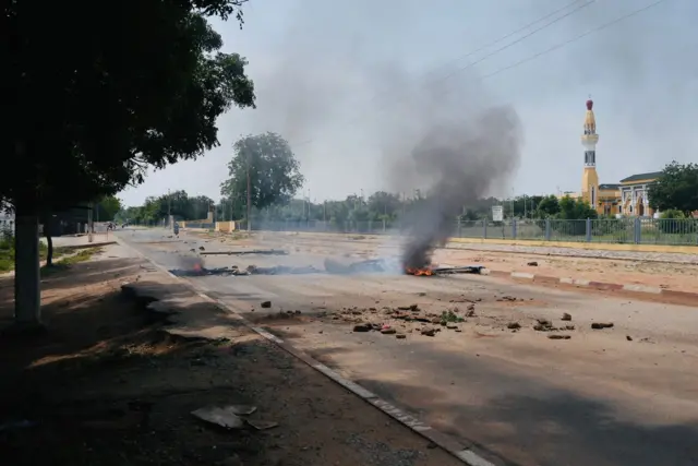 Une rue déserte et jonchée de pierres avec un feu au milieu de la chaussée