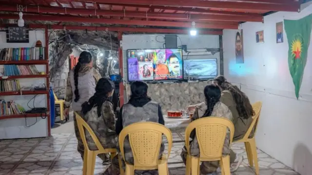 पीजेएकेचे सदस्य टीव्हीवरील बातम्या पाहून बोगद्याच्या बाहेरील घटनांवर लक्ष ठेवतात.
