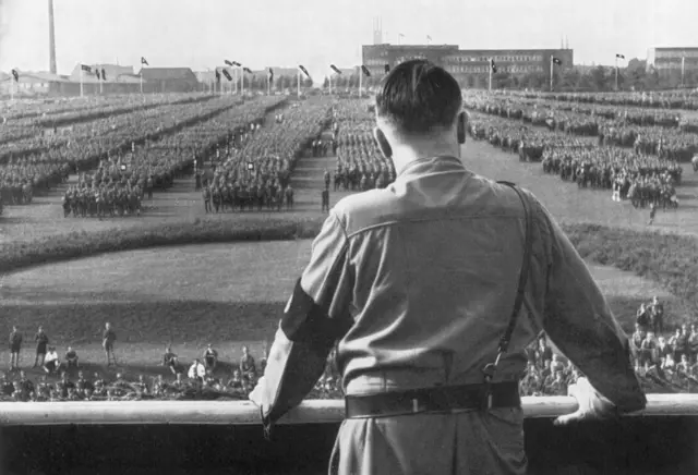 Hitler aparece de costas, olhando para soldados, perfilados, durante comício nazista em Dortmund, Alemanha