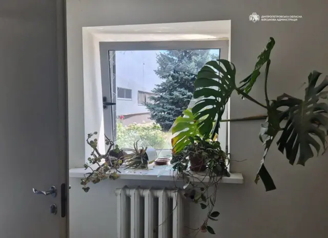 У приміщені вибите вікно, на якому стоять вазони 
