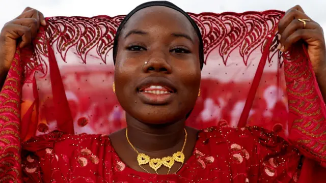 A Ivory Coast wata Musulma ta sanya jan kaya tana gyara hijabinta, gashin kanta a rufe ya yin shagulgulan bikin Salla