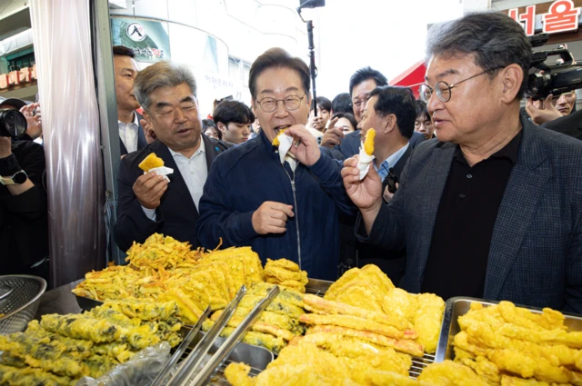 더불어민주당 이재명 대선 후보가 '골목골목 경청투어' 접경지역 방문 이틀째인 2일 강원 철원군 동송전통시장에서 튀김을 먹고 있다