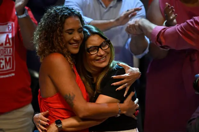 Anielle e Janja abraadas e sorrindo durante comcio