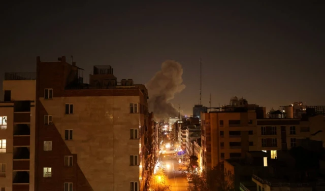 Tahran'da gece karanlığında duman ve kızıl patlama rengini görüyoruz. Binalar var kadrajda ama patlama yerini görmüyoruz.