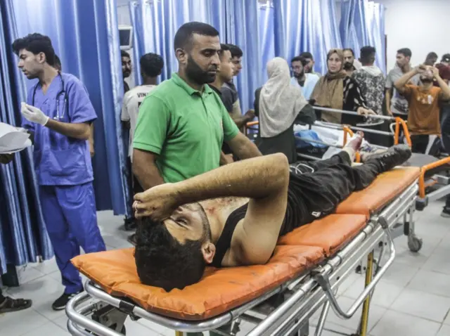 صورة لمصاب يستلقي على سرير داخل المسشتفى الإندونيسي محاط بأشخاص كثيرة.