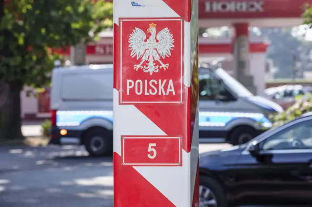 Biało-czerwony słup graniczny z białym orłem i napisem Polska. Na drugim planie samochody, na przejściu granicznym Porajów, Polska, 3 lipca 2025